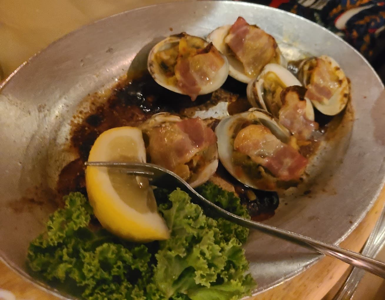 Classic clams casino topped with bacon in a metal pan with lemon