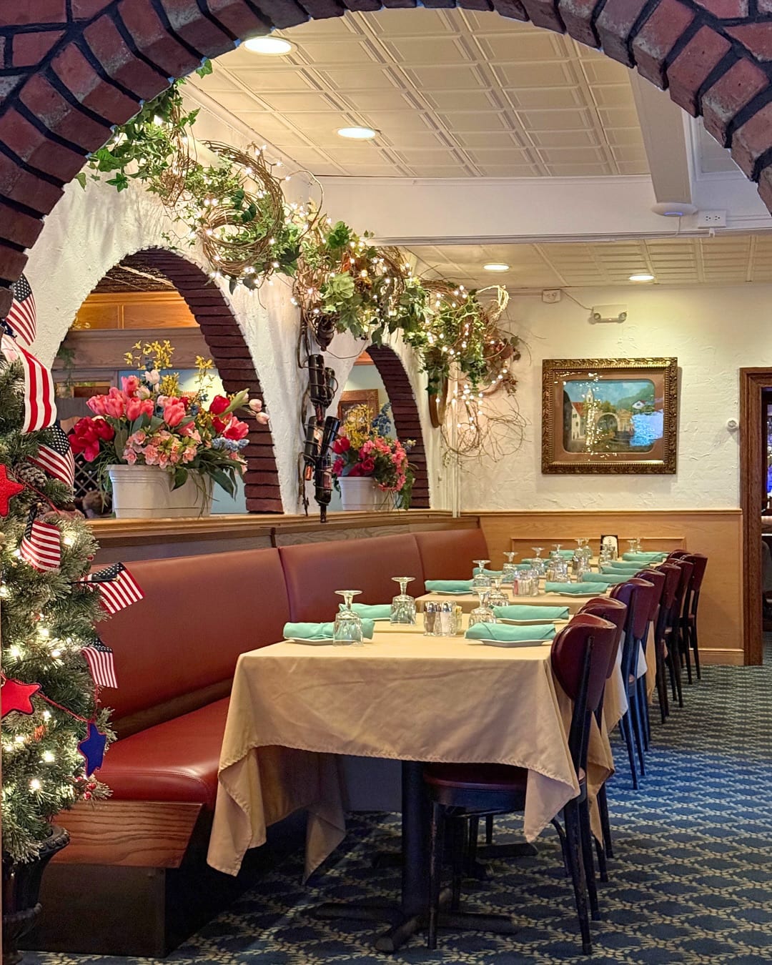 Brick archways and a red banquette in Mario's dining room, dressed with flowers