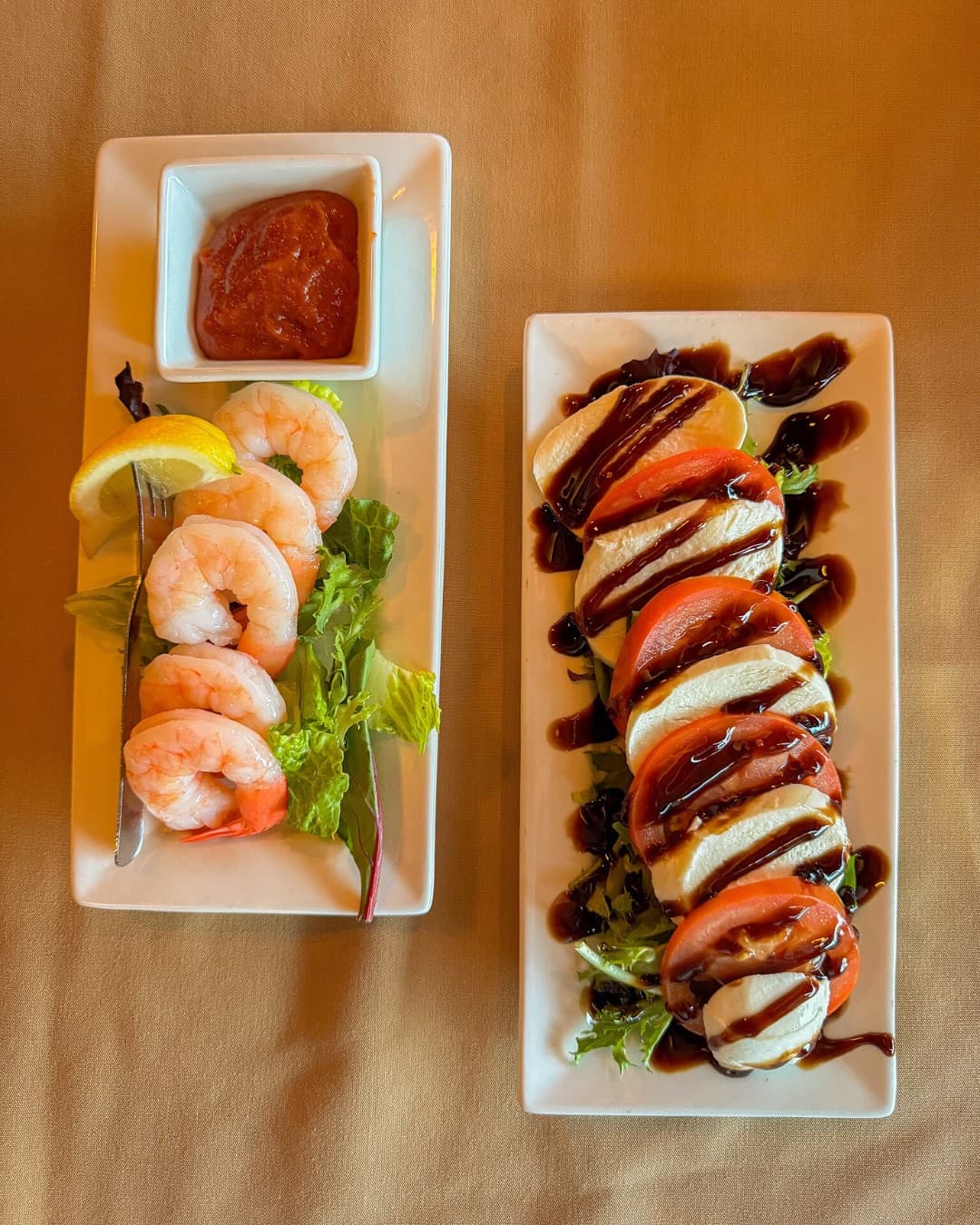 Shrimp cocktail beside a caprese salad drizzled with balsamic