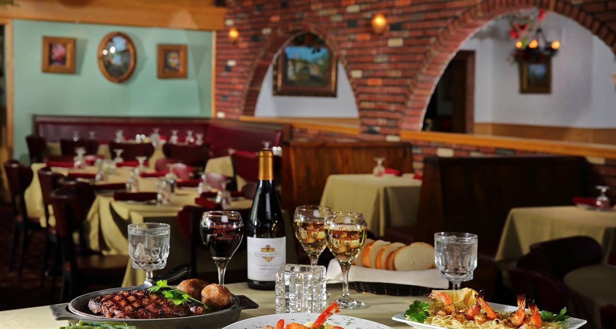 A table at Mario's set with a charbroiled steak, shrimp scampi, wine and fresh bread before the brick archways